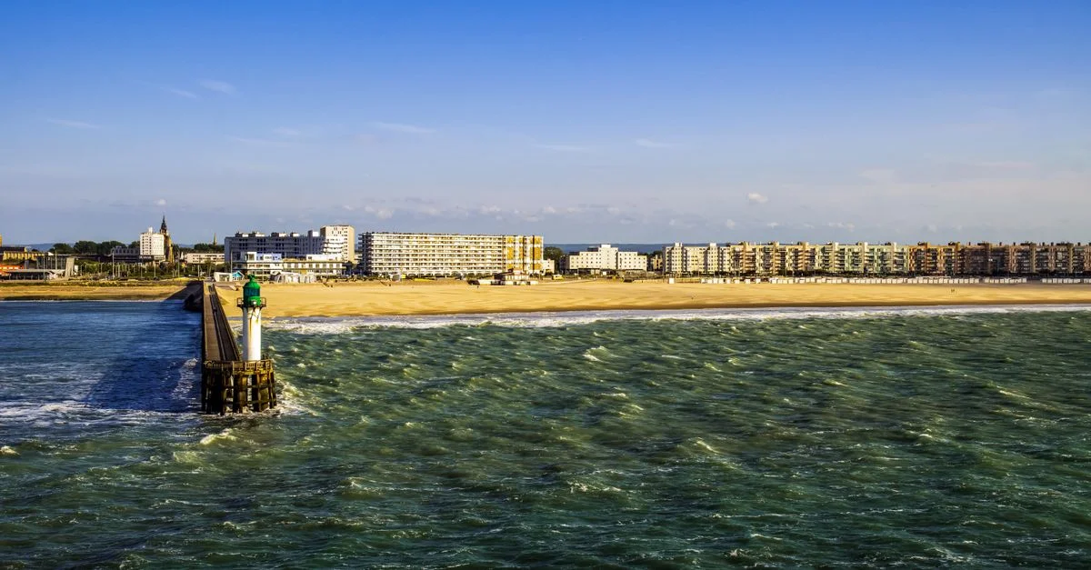 Vue vibrante sur le bord de mer de Calais, France, avec le quai, la plage de sable et la ville.