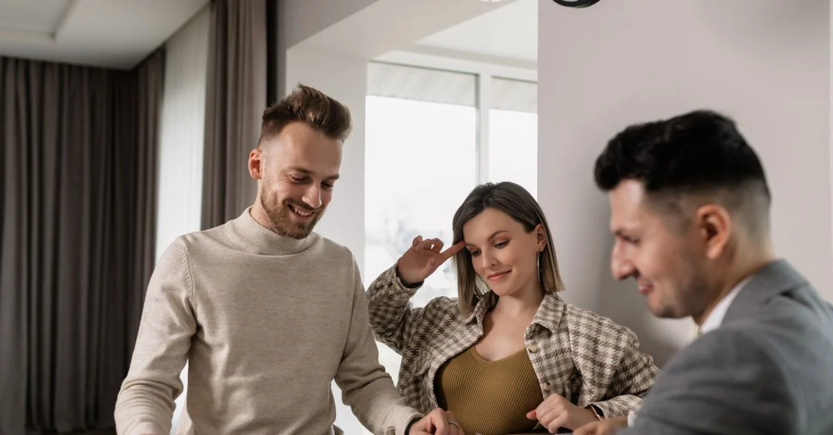 Un couple consulte un agent immobilier dans une pièce confortable, examinant des plans de logement.