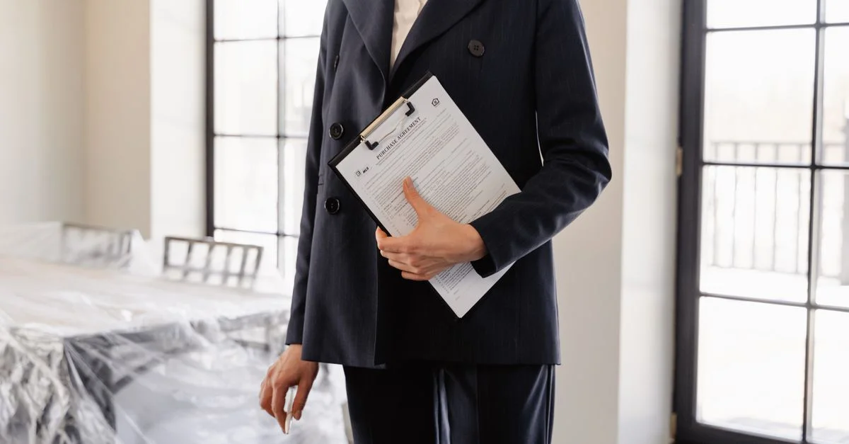 Agent immobilier professionnel tenant des documents dans une pièce ensoleillée, symbolisant le succès et les transactions.