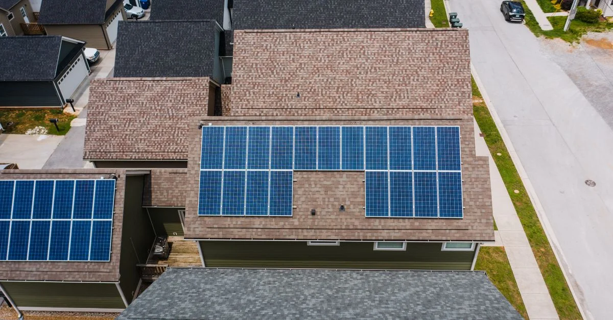Photo par drone des panneaux solaires sur des toits résidentiels promouvant des solutions énergétiques écologiques.