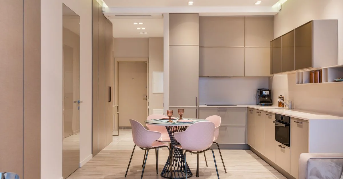 Cuisine contemporaine minimaliste avec une table à manger ronde et des chaises pastel, idéale pour les appartements urbains.
